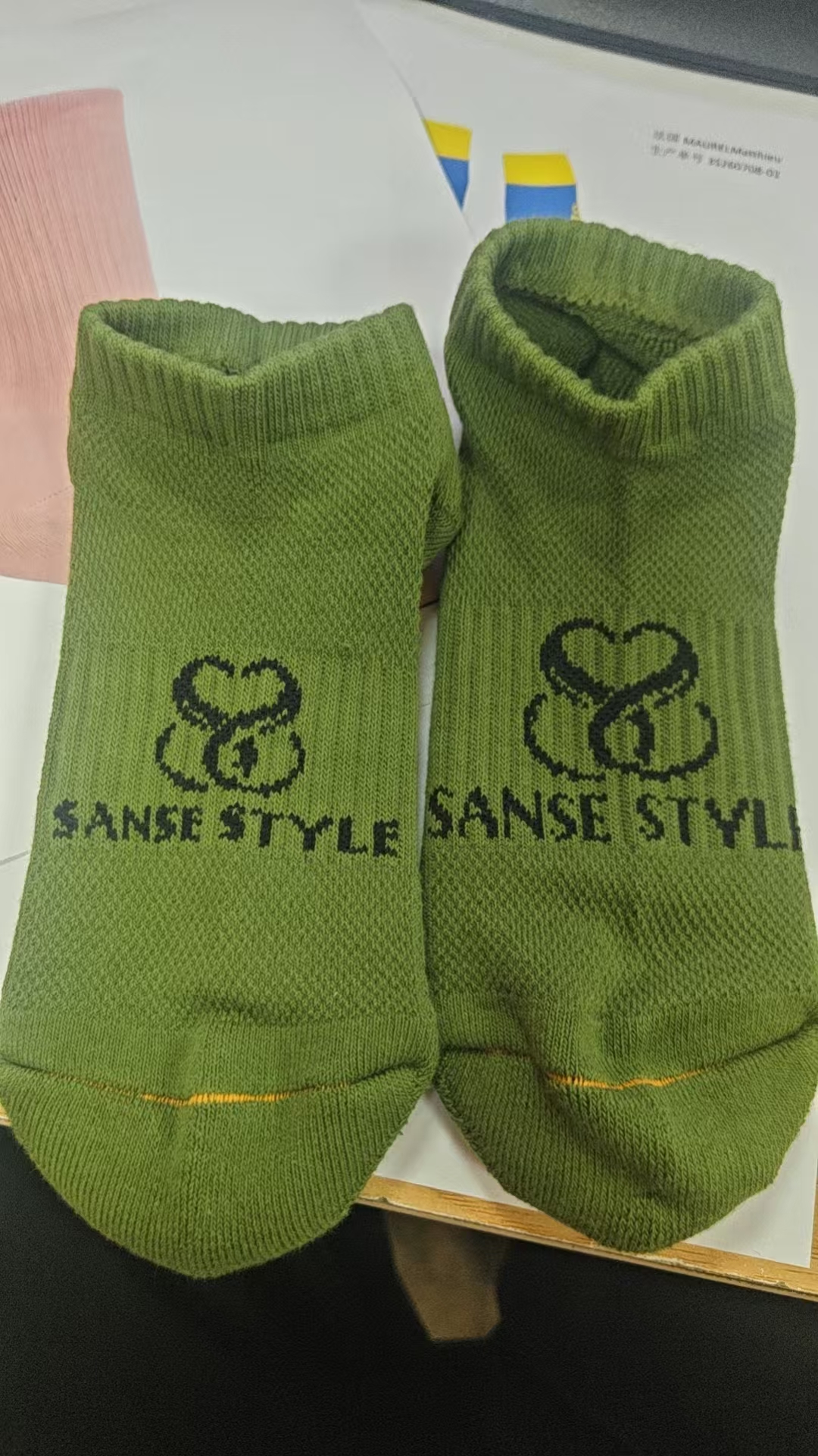 Green low-cut branded sock sample showing knitted logo
