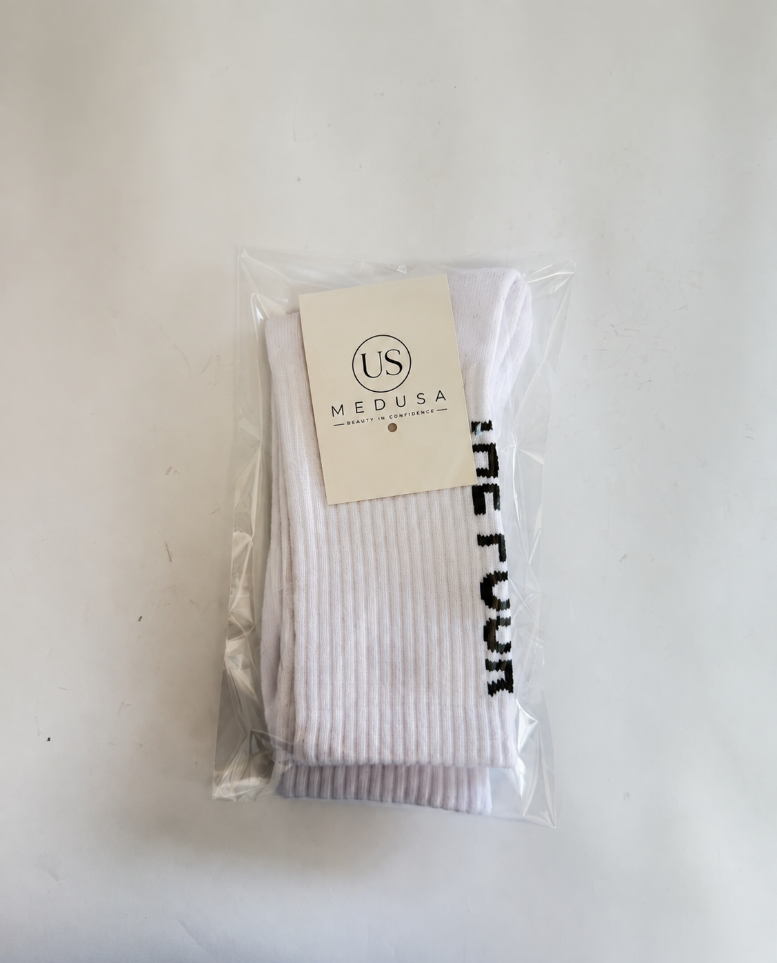 Branded crew socks folded in a clear retail bag with US MEDUSA card
