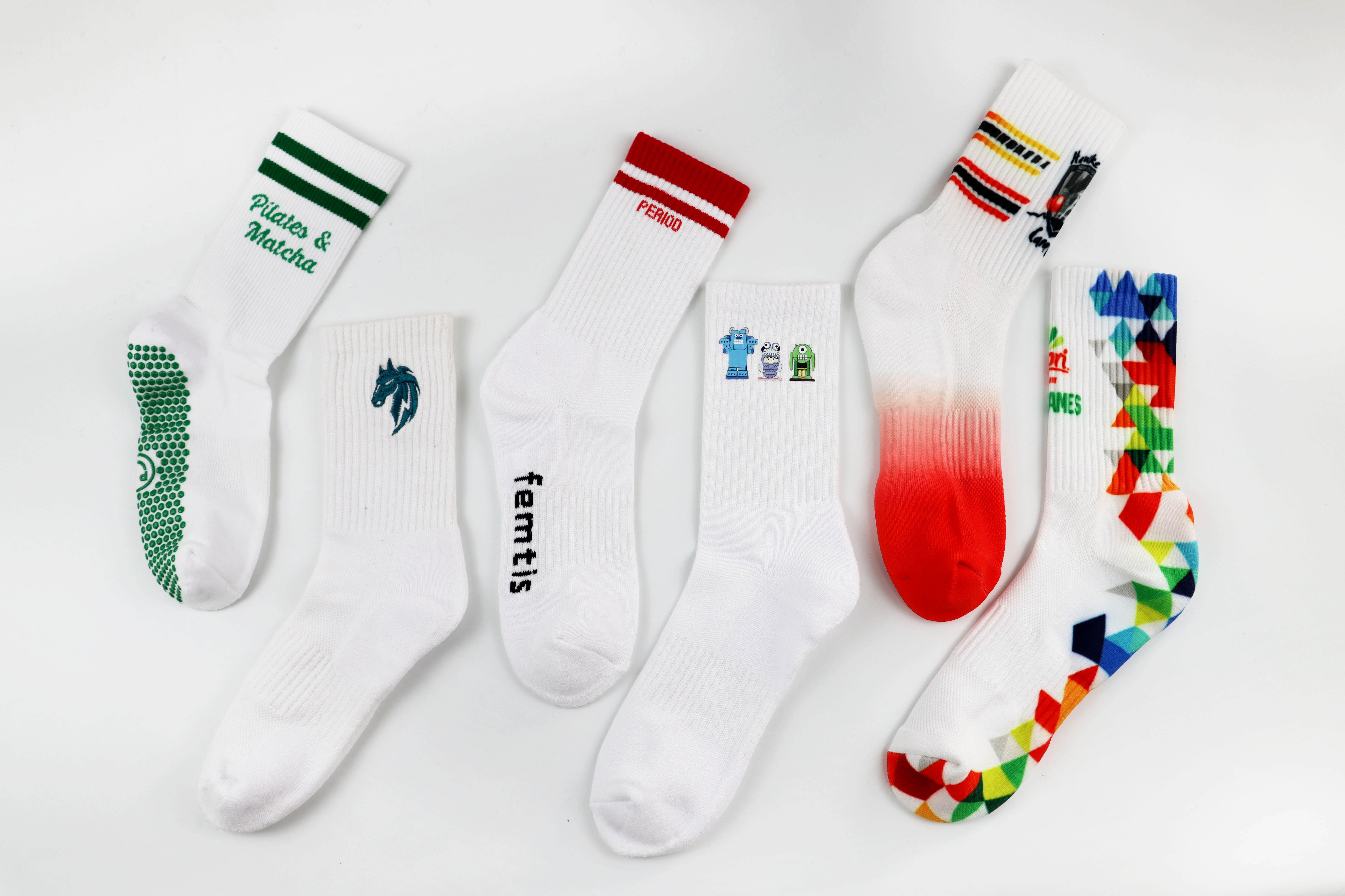 Six white custom socks showing grip prints, logos, stripes and multicolor graphics